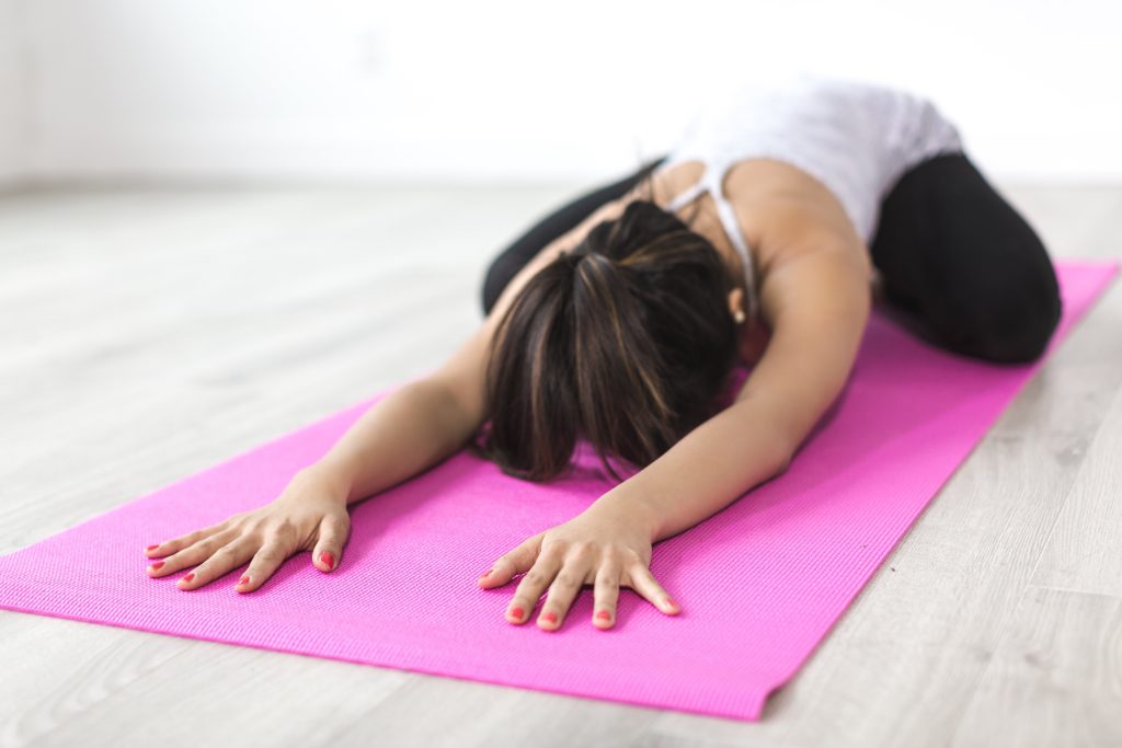 Eine Frau ist auf einer Schaumstoffmatte und macht eine Yogaübung, um Schmerzen im unteren rechten Rücken vorzubeugen