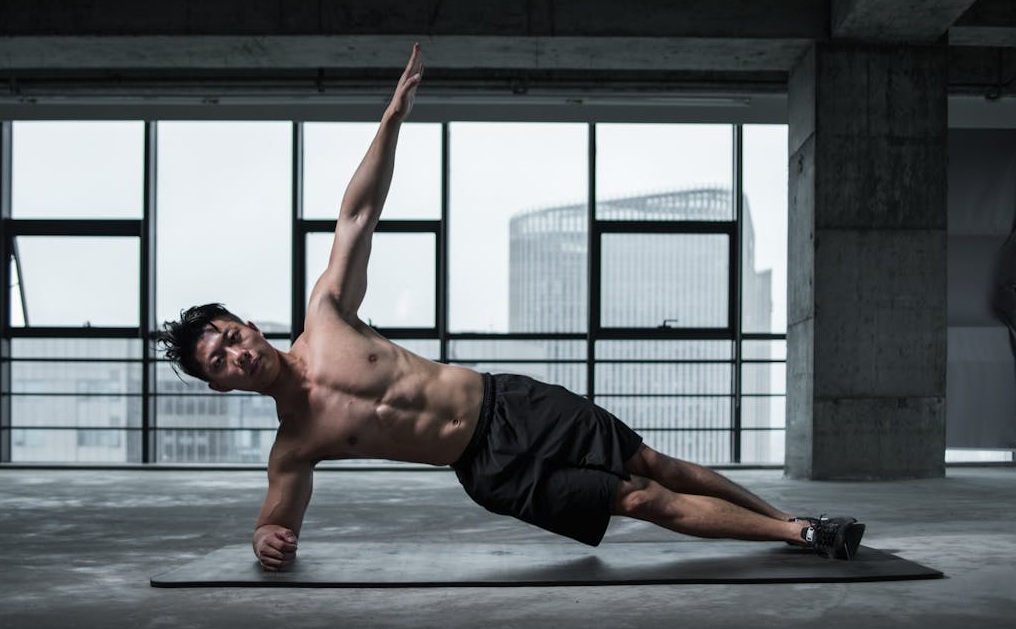Ein Mann führt auf einer Matte den seitlichen Unterarmstütz aus. Seitliche Planks sind sehr gut geeignet, um das Training für den unteren Rücken zu ergänzen