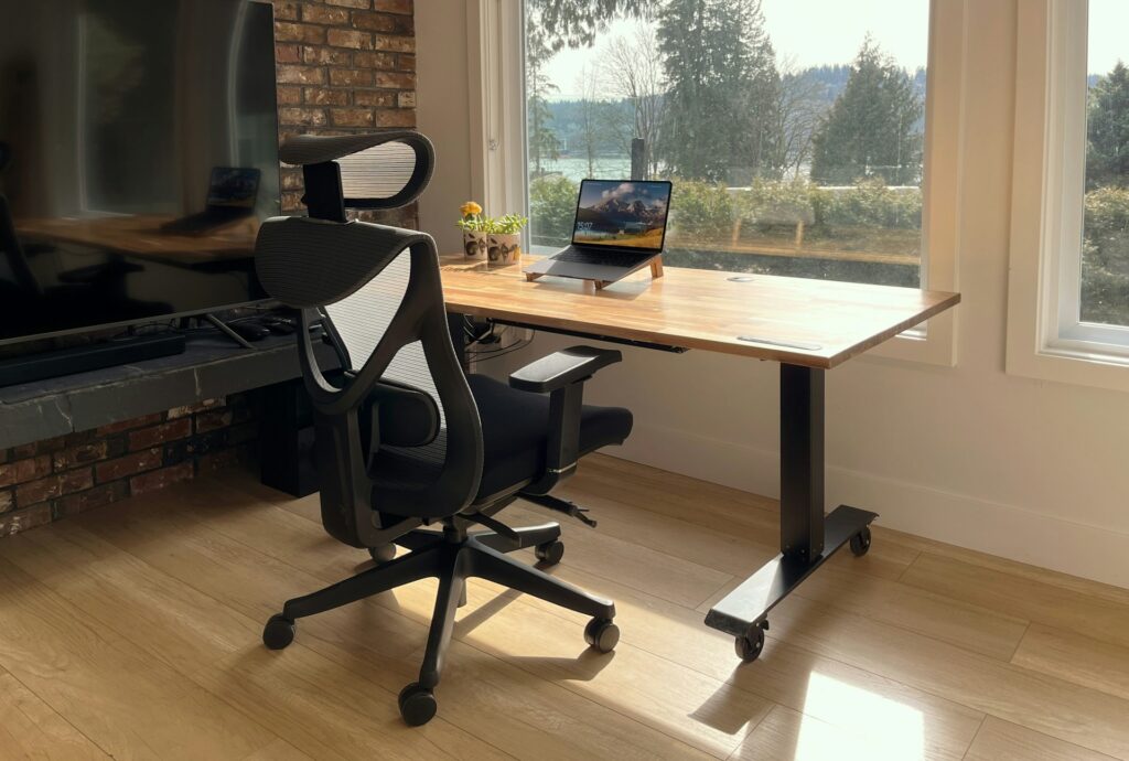 Ein ergonomischer Bürostuhl steht vor einem höhenverstellbaren Schreibtisch